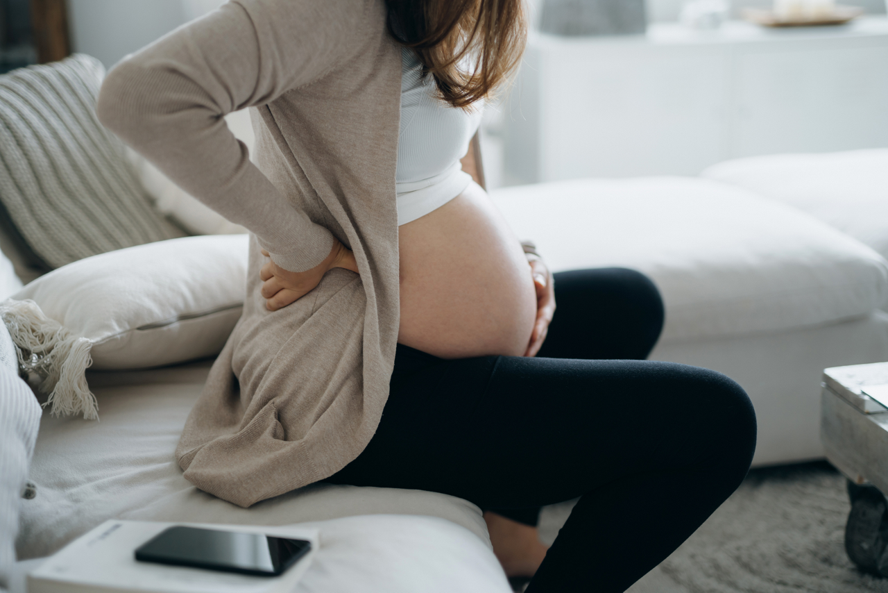 Pregnant woman sitting on couch with smartphone
