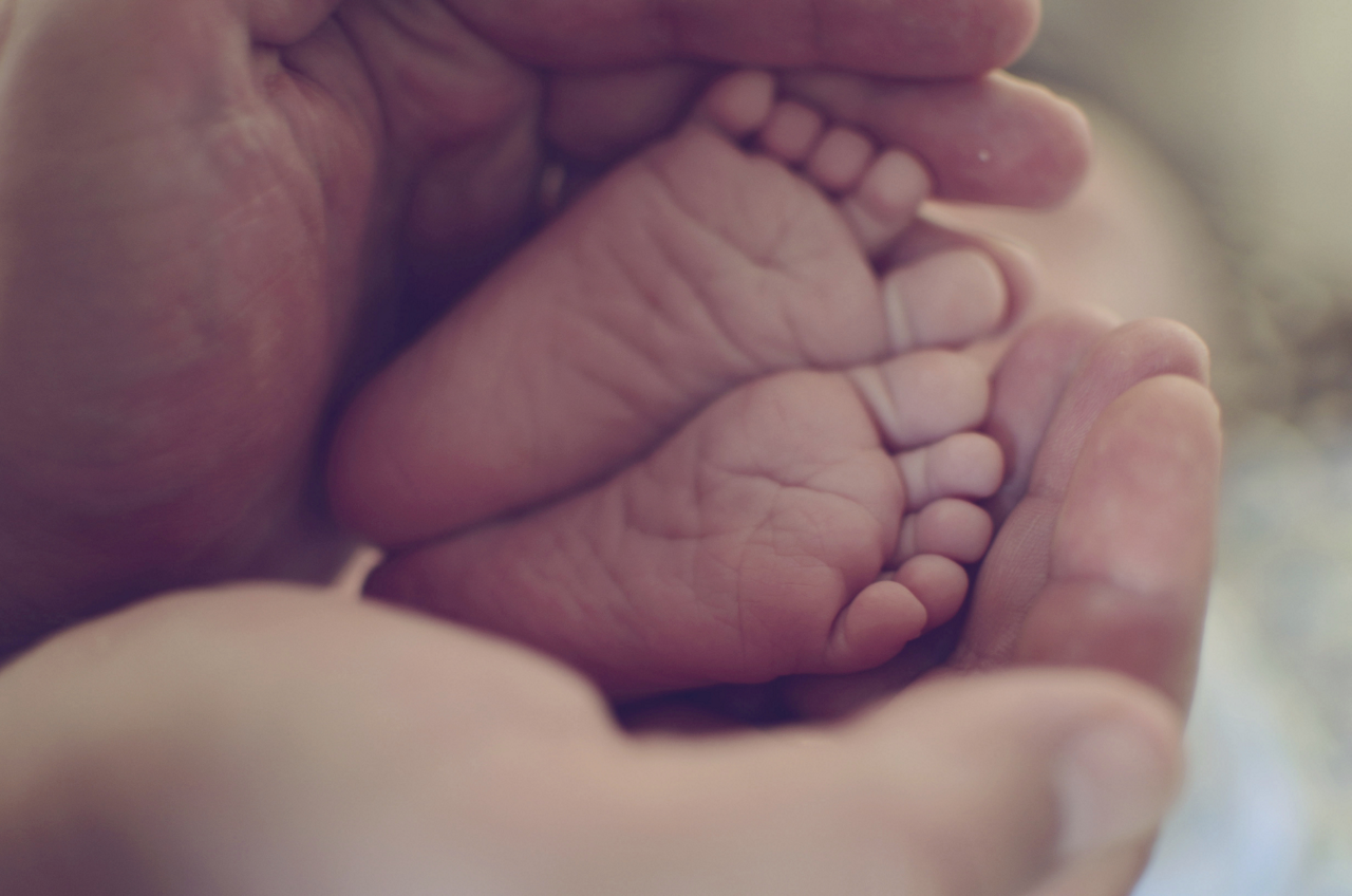 Mom and dad holding their newborn baby's foot gently