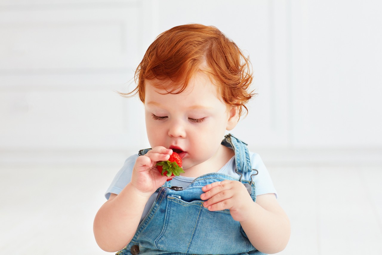 Rothaariges Baby nascht Erdbeere
