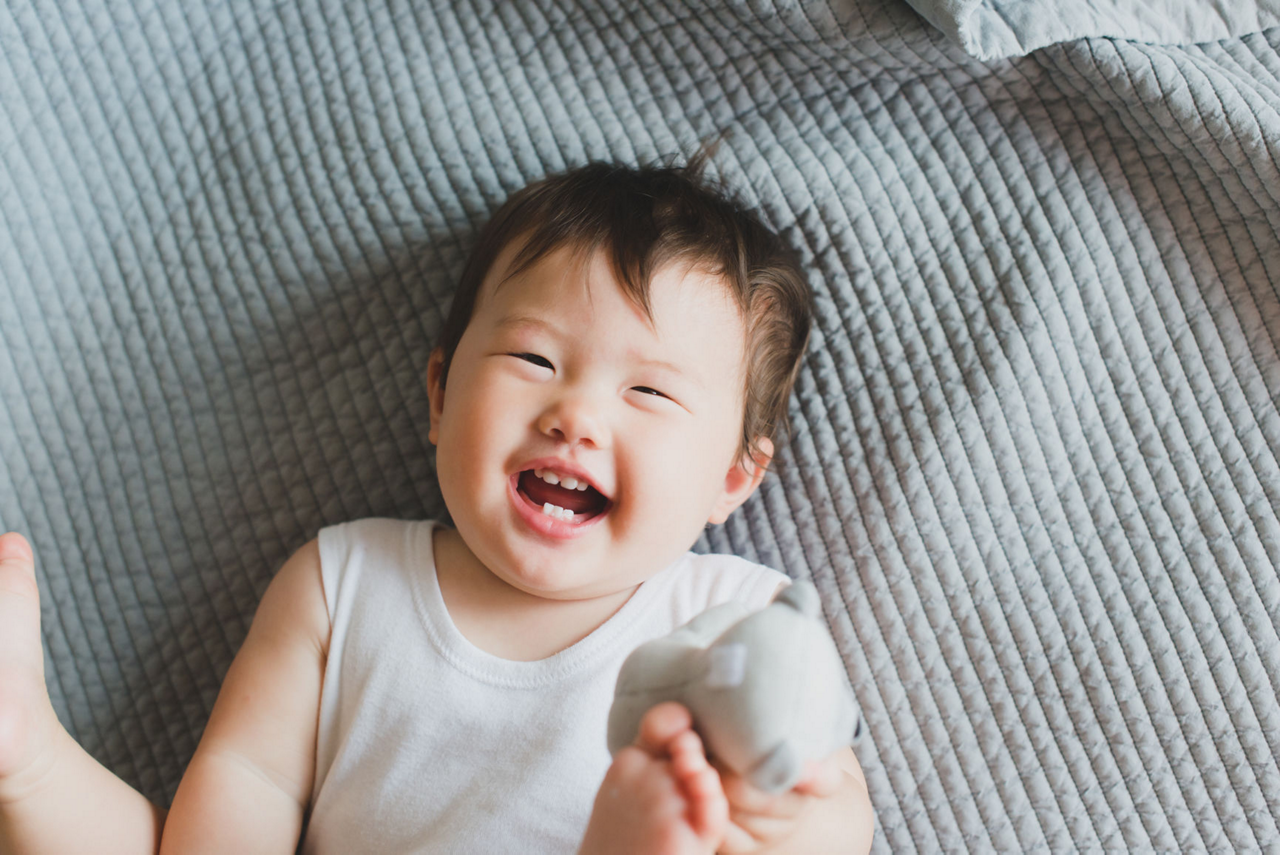 Baby boy laughing on bed
