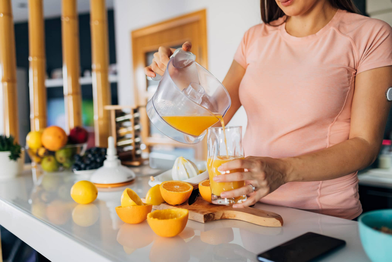 Milupa AT Schwangere gießt Orangensaft in Glas