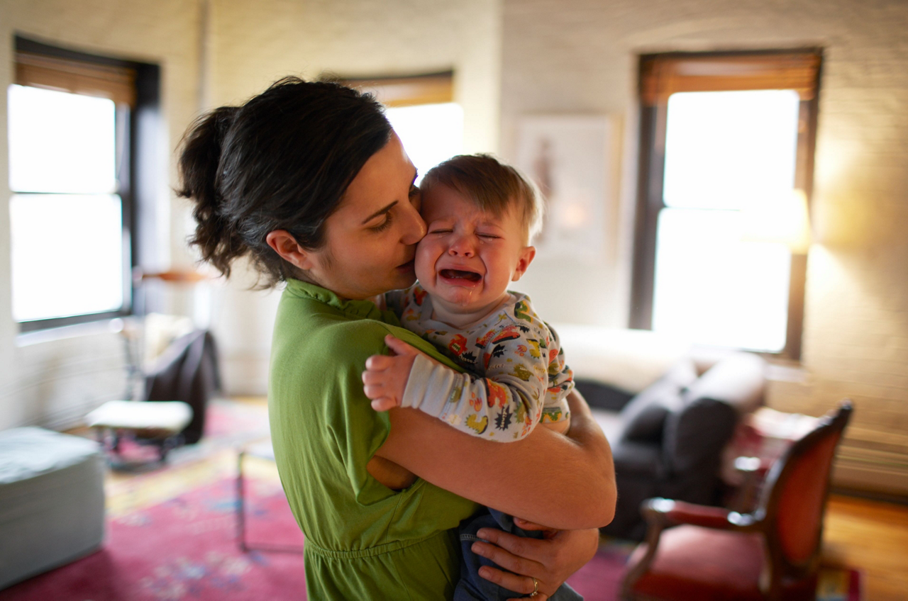 Frau hält weinendes Baby im Arm 