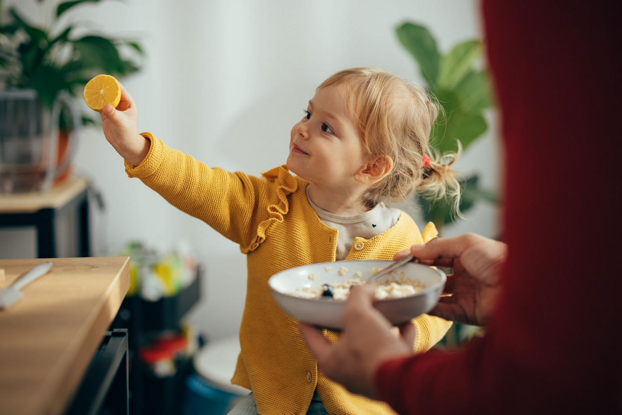 Kleines Mädchen hält Zitrone in der Hand 