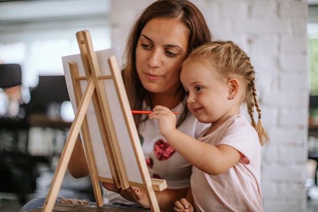 Kind mit Mama beim Malen auf einer Leinwand