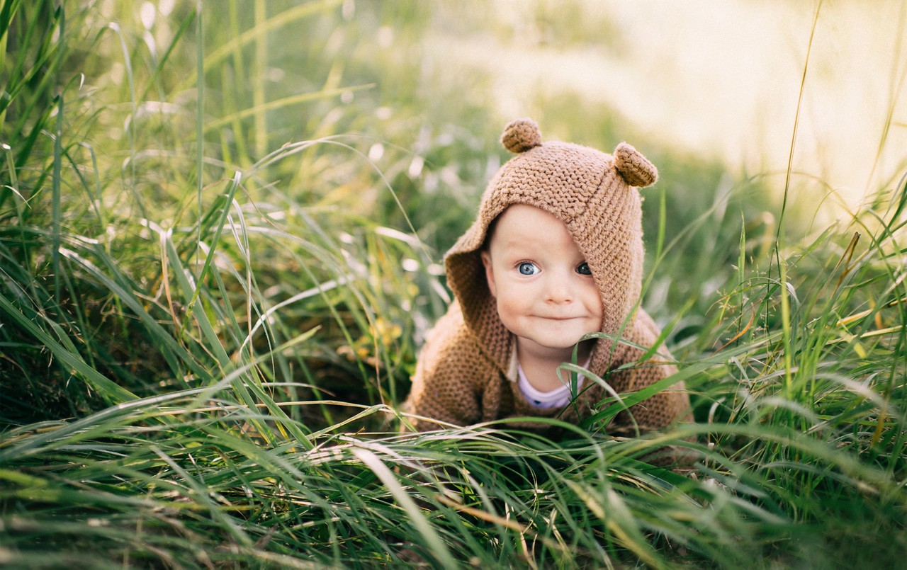 Baby sitzt im Gras und lächelt 