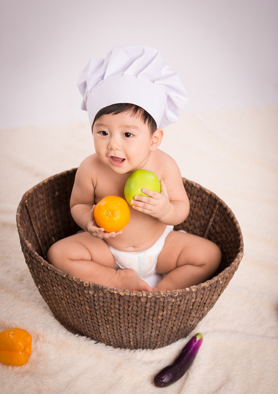 Little baby boy playing with fruits.