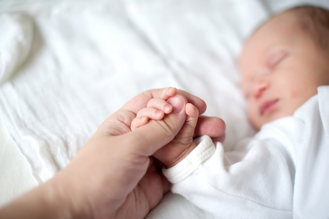 parent holding babys hand whilst sleeping
