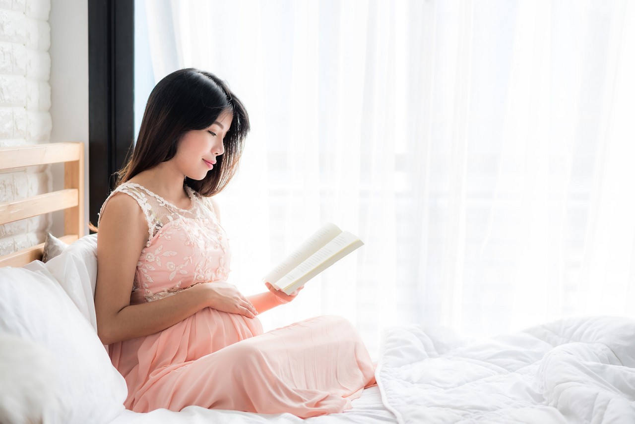 19th-week pregnant woman reading a book before bed