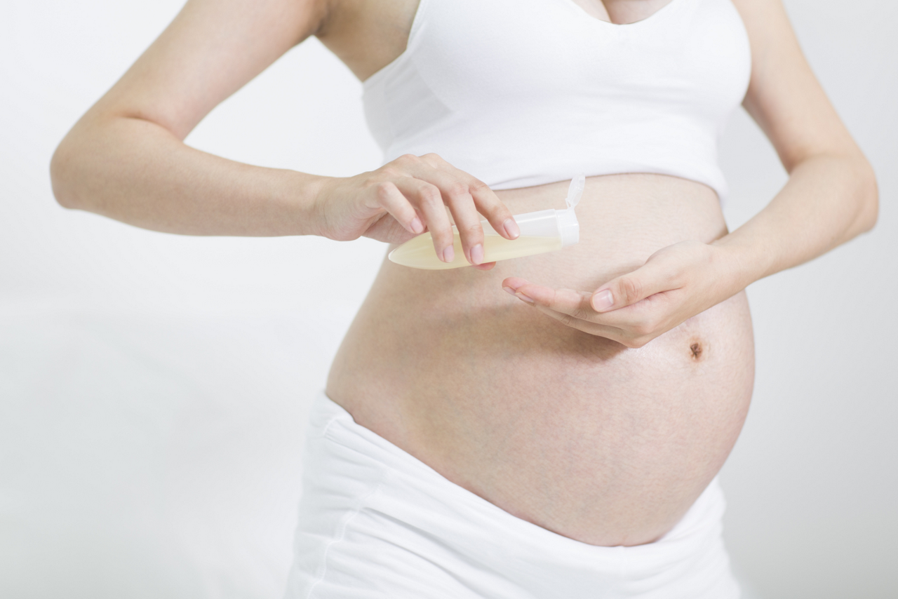 Schwangere cremt Babybauch ein