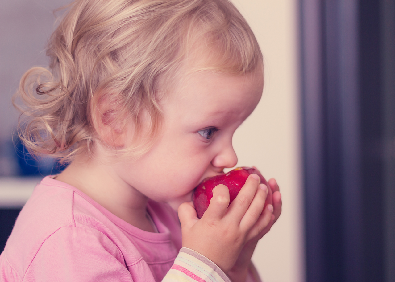 Toddler girl eating peach