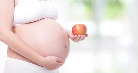 pregnant woman hand holding red apple