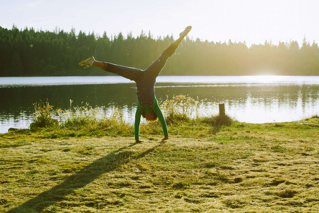 Eine Frau schlägt ein Rad am Ufer eines Sees.