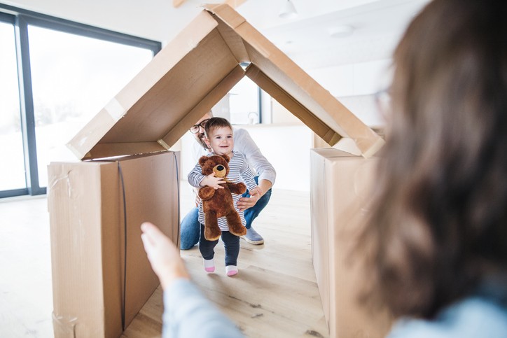 A young family with a happy toddler girl indoors, moving in new home concept.