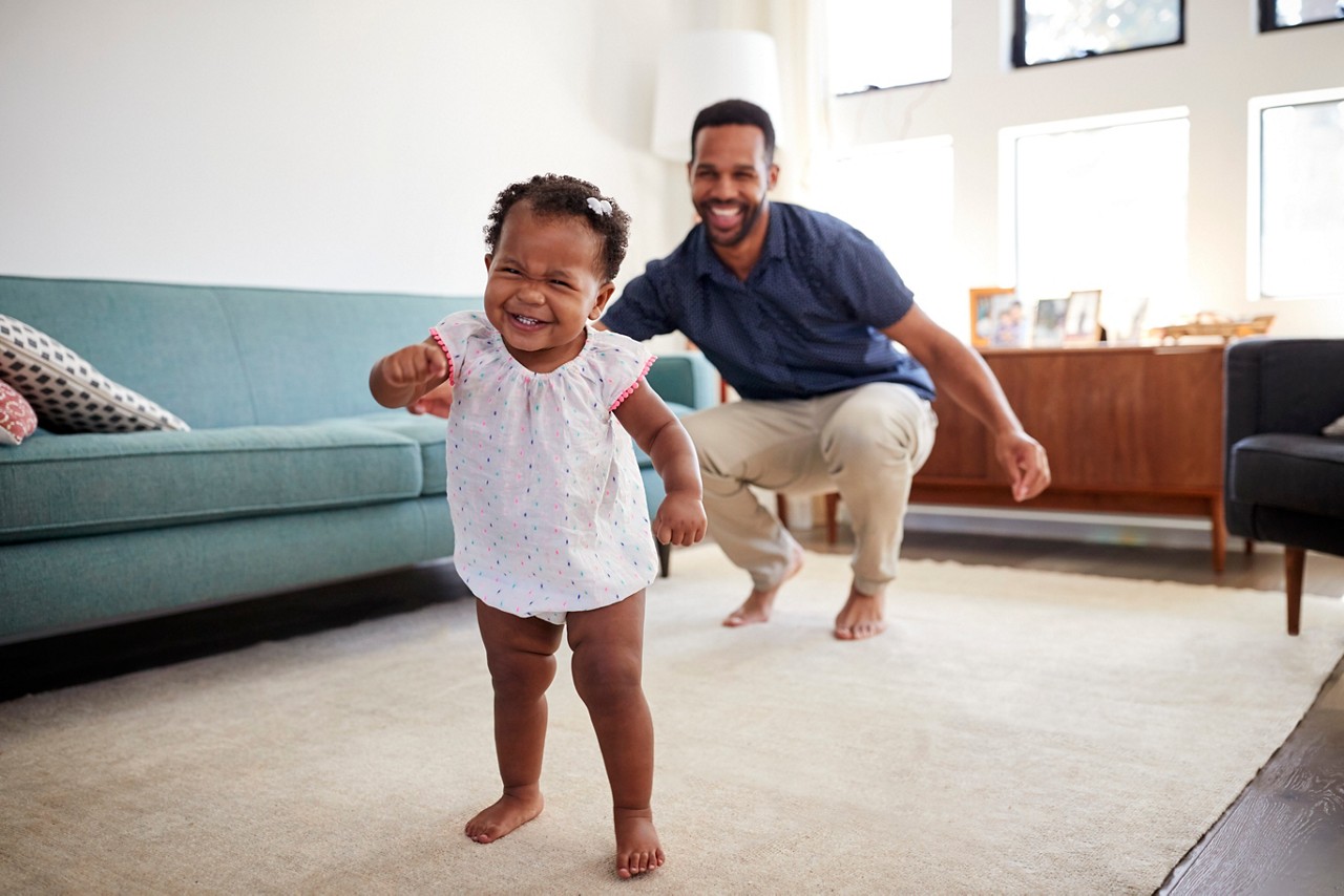 Baby Daughter Dancing With Father In Lounge At Home