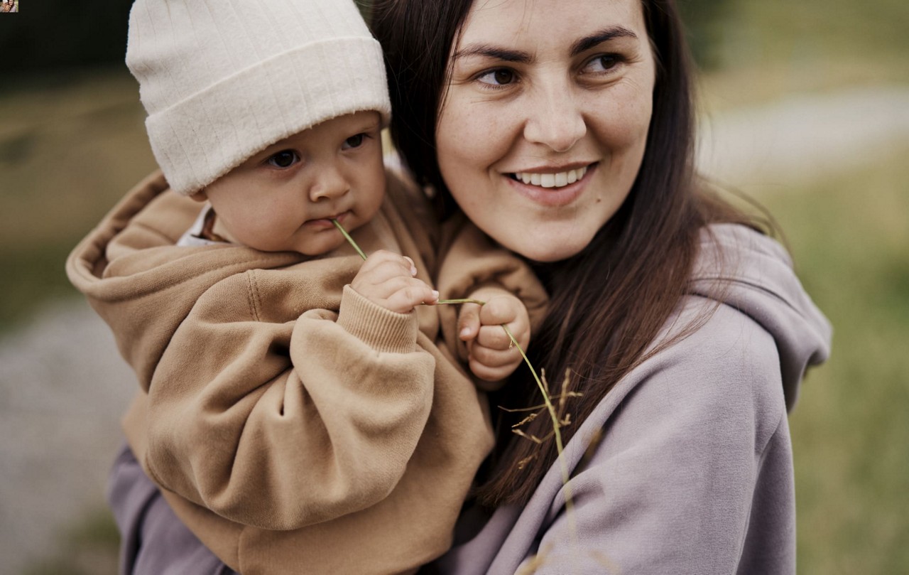 Maman tient bebe bras montagne gros pull