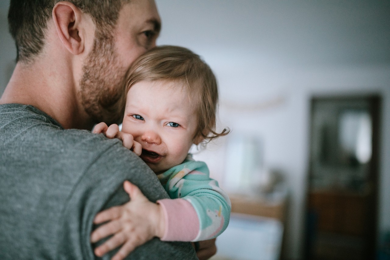 Cold and flu season takes its toll, with babies and small children even more susceptible to illness.  A dad holds his baby girl, trying to comfort her in the midst of her sickness.