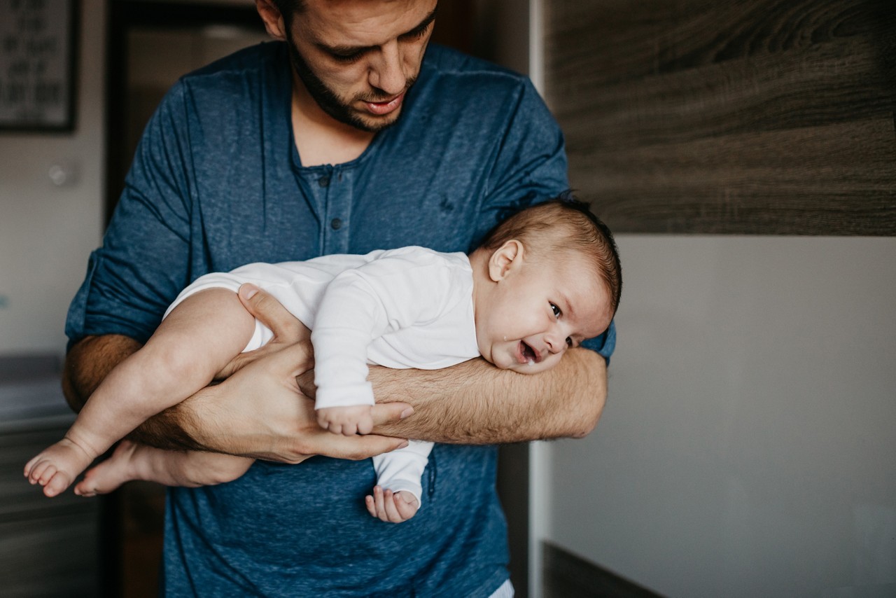 Newborn baby boy crying in his father's arms