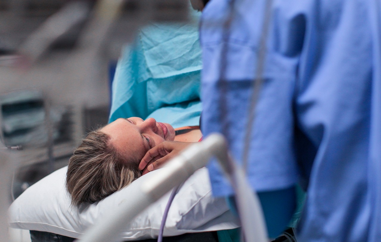a Young pregnant woman lays on the operating table moments before a caesarean section