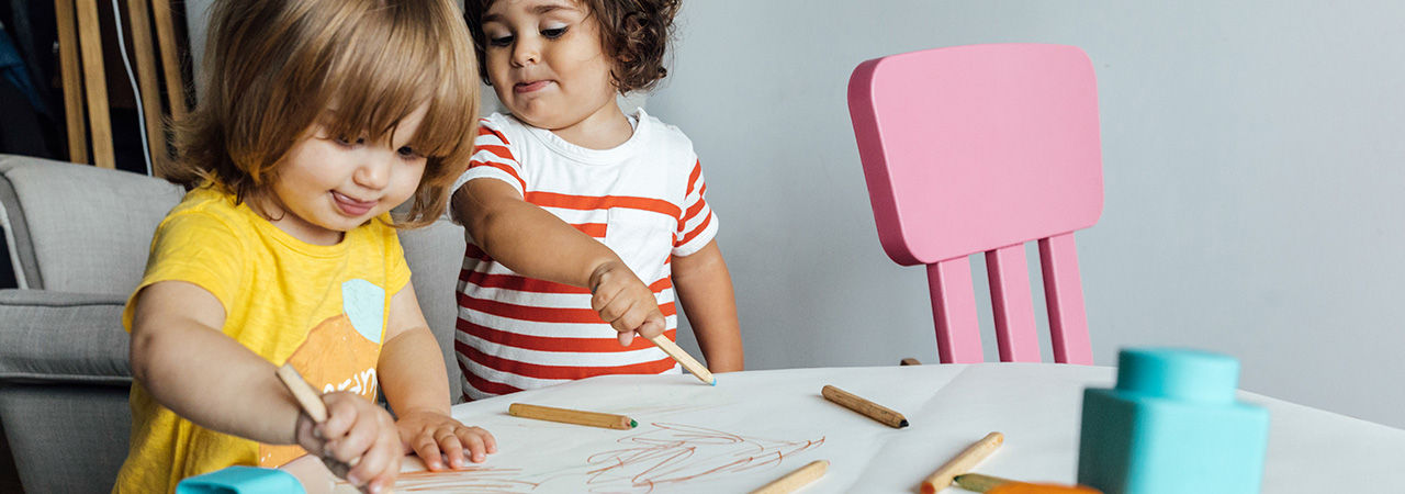 From above of preschool kids playing with colorful blocks and drawing while spending time together in playroom of modern kindergarten. Children learning concept