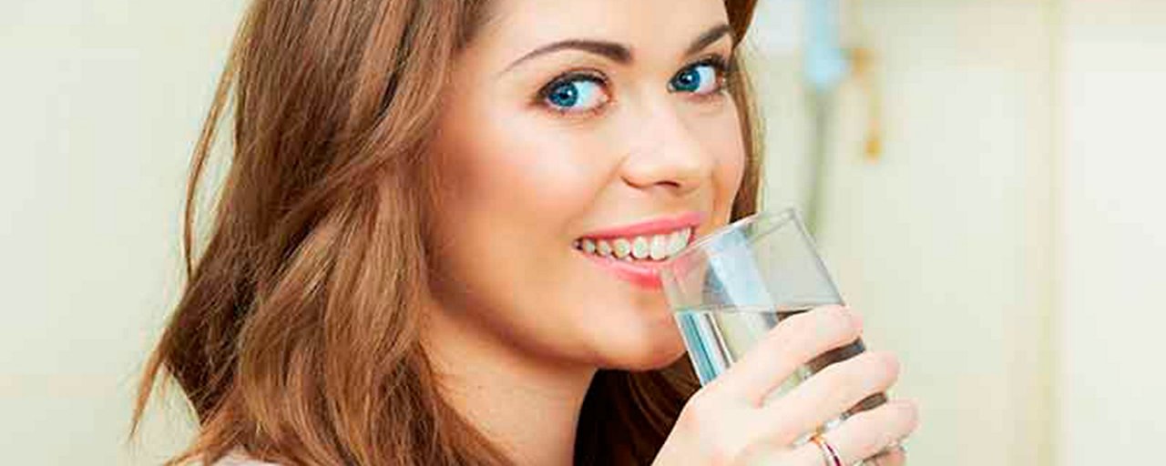 Donna bene un bicchiere di acqua