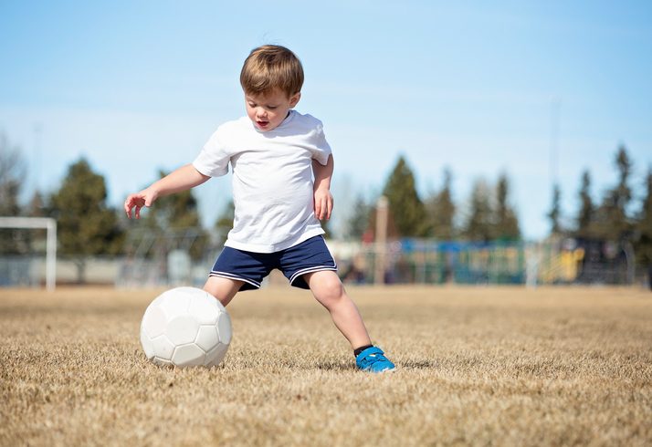 Toddler plays with soccer ball on spring field