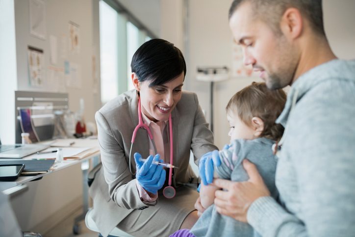 Pediatrician giving baby girl vaccination in clinic