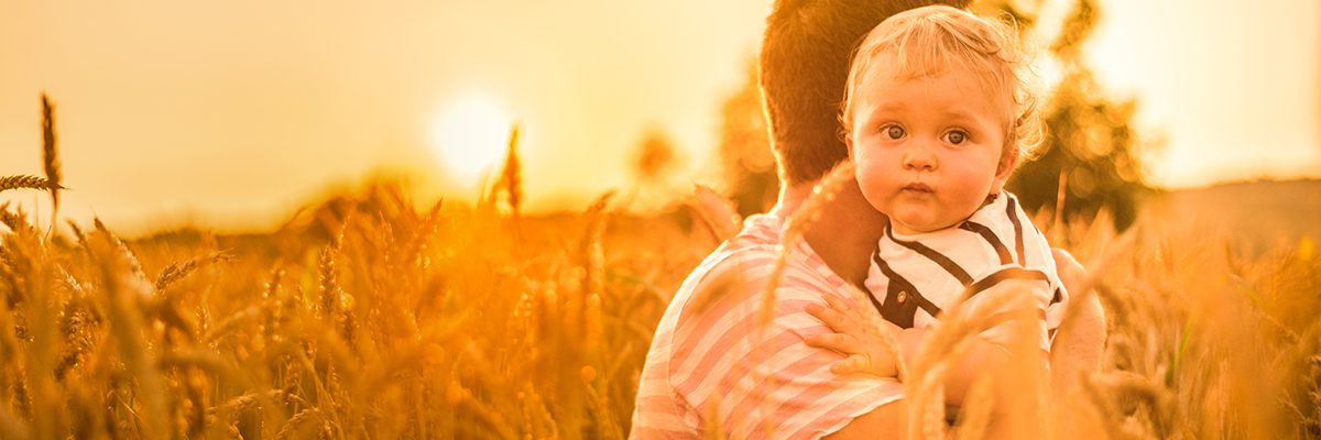 Vater mit Baby im Arm im Getreidefeld