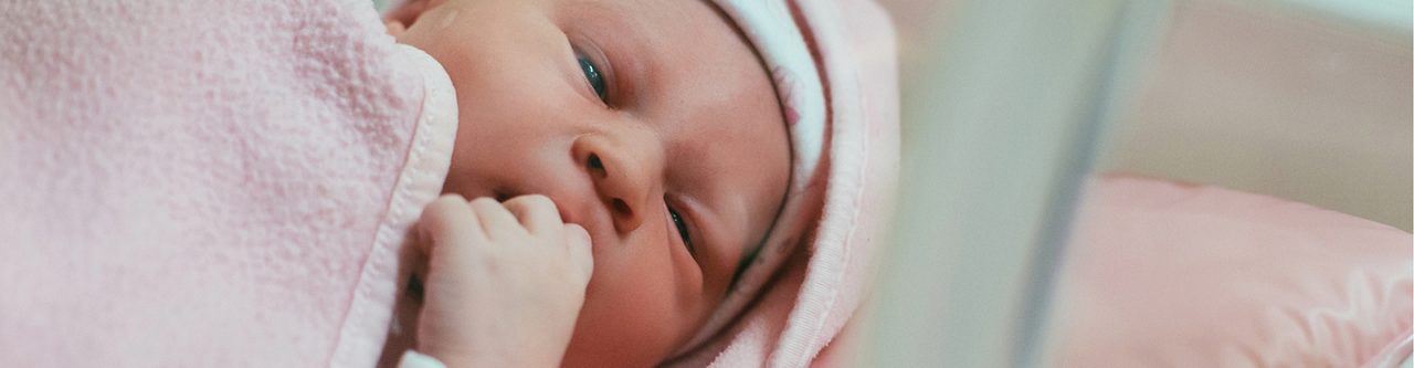 Newborn baby tucked in sheets