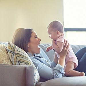 Mere tenant son bebe sur un canape