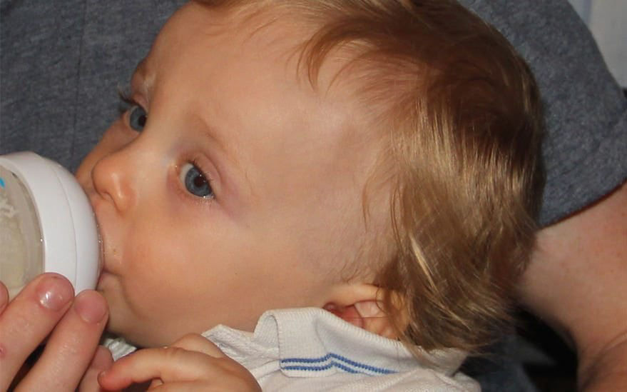 Bebe buvant au biberon a l'interieur