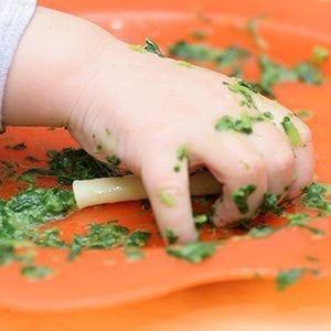 Main de bebe jouant avec de la nourriture sur un plateau