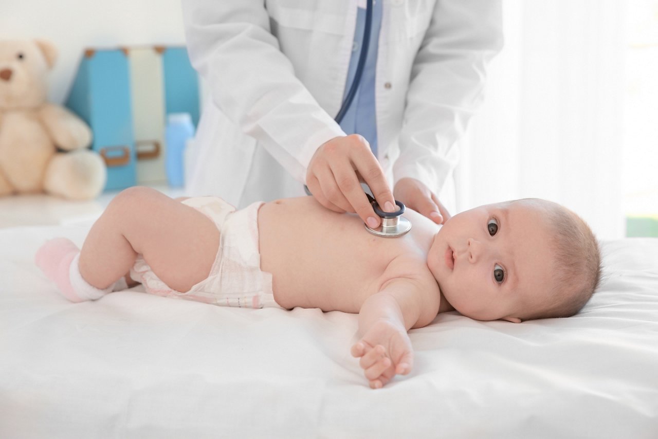 Doctor examining baby with stethoscope in clinic