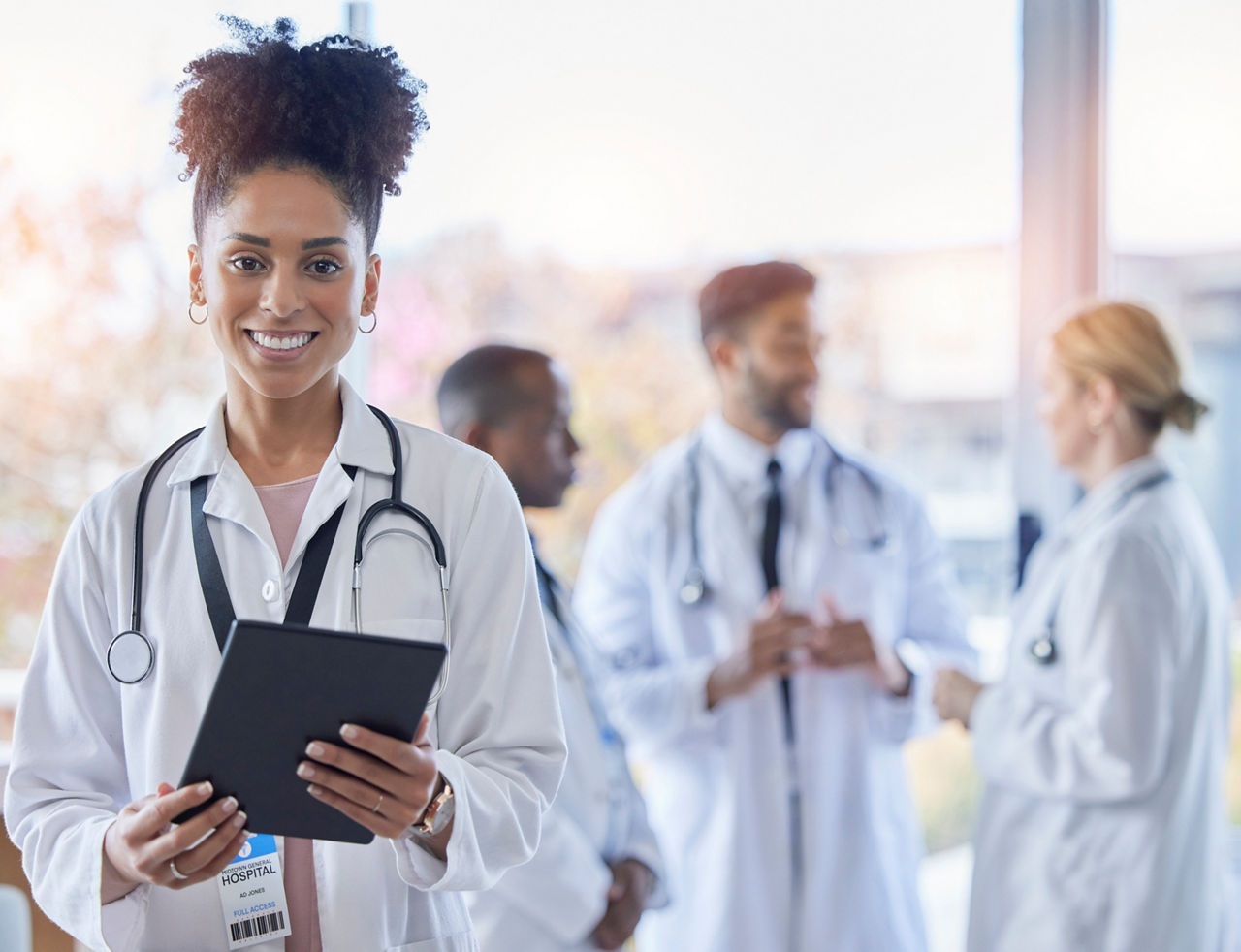Black woman, doctor portrait and tablet with medical team in hospital ready for healthcare work. Wellness, health and medic employee in a clinic feeling happiness and success with blurred background
