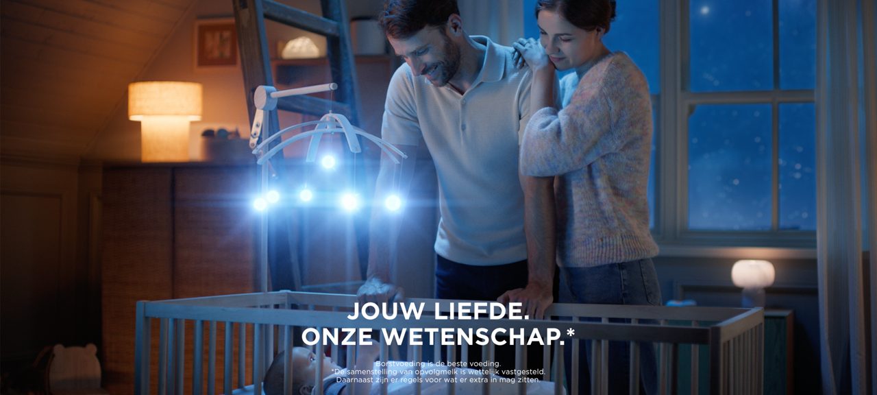 Ouders bij een babybedje met een verlichte muziekmobiel, onderdeel van de Nutrilon-campagne Jouw liefde. Onze wetenschap.