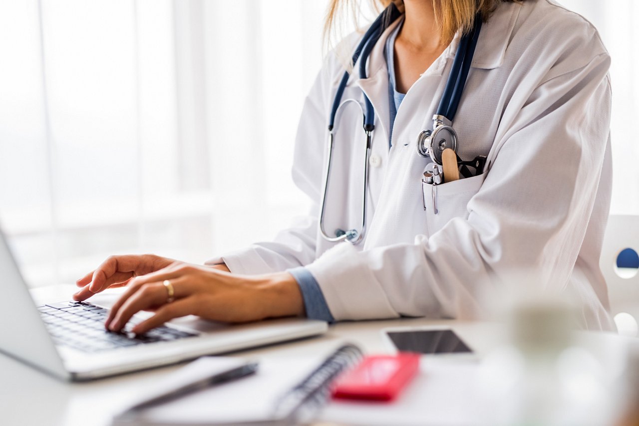 Doctor working on laptop at the office desk.
