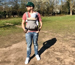 Vater mit Baby in der Trage im Park