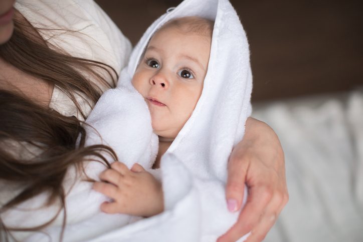 Cute baby boy covered in towel after bath