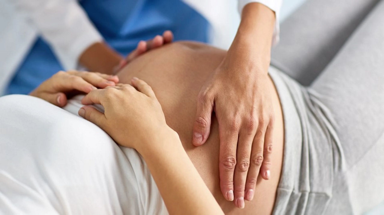 Doctor feeling expectant mothers bump