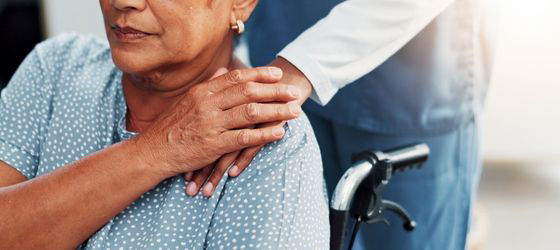 A woman in a wheelchair holding hands with a doctor
