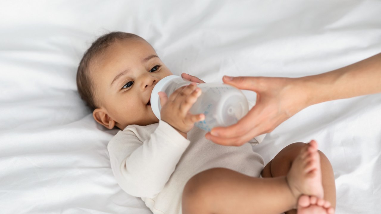 Closeup of infant drinking milk or water baby bottle