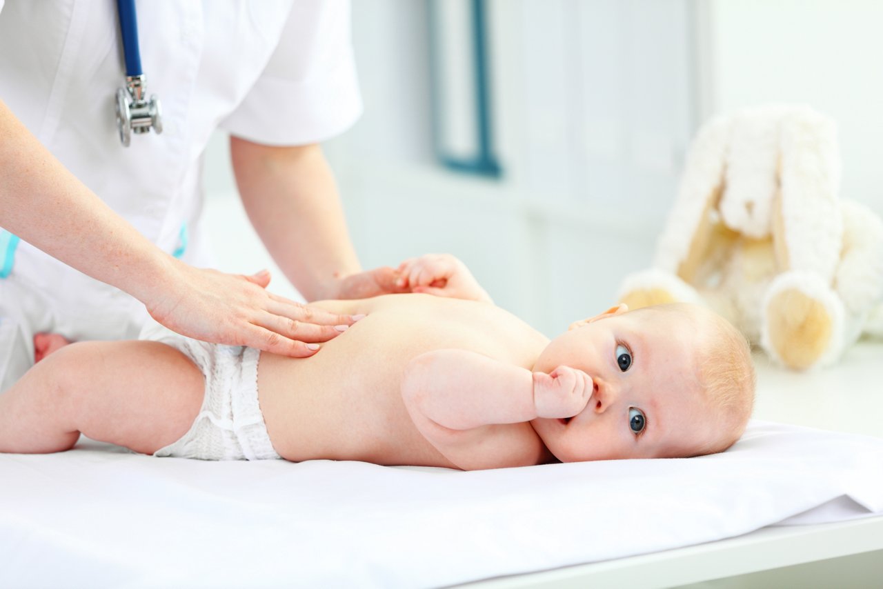 Doctor pediatrician examines the baby tummy