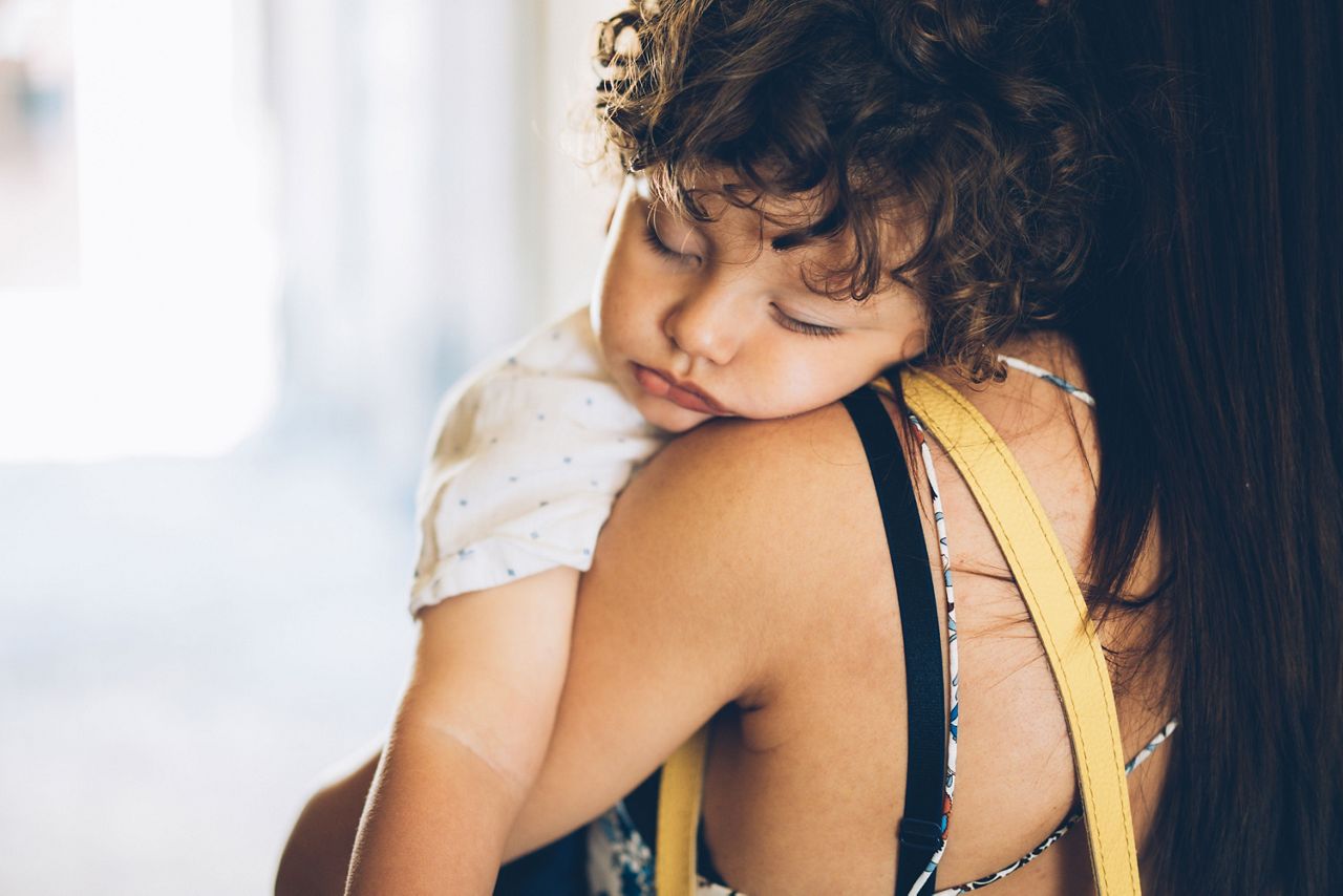 Kleinkind schläft auf der Schulter der Mutter