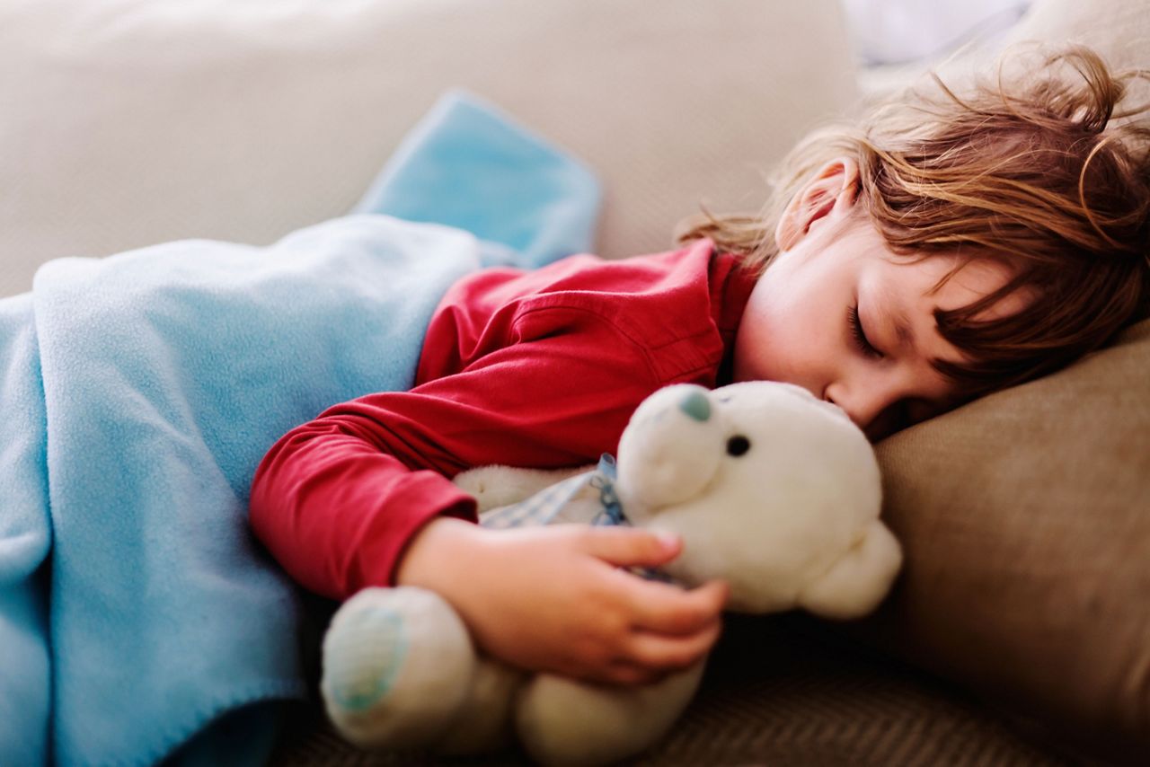 Kleinkind kuschelt mit Teddy im Bett rechts