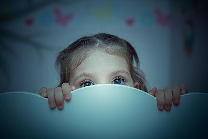 Kleinkind versteckt sich hinter Bettchen abends