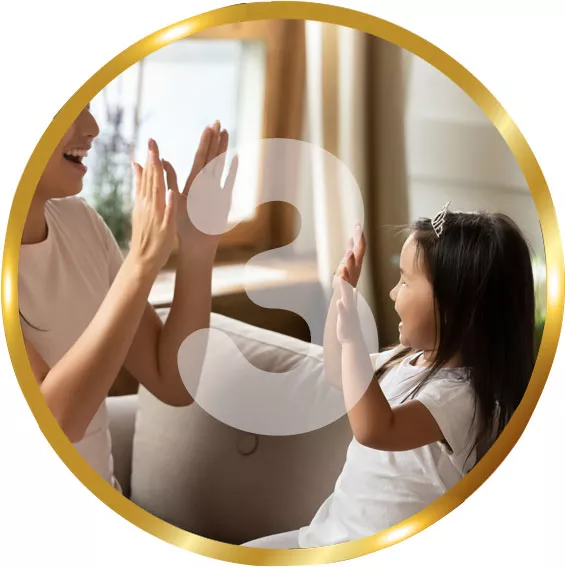 A woman and a young girl sit on a sofa playing a clapping game together. The scene takes place in a cozy living room with soft natural light coming through the window. Both are smiling and wearing light-colored clothing, creating a warm and tender family moment. The image is framed by a circular gold border with a large translucent number 3 overlaid in the center.