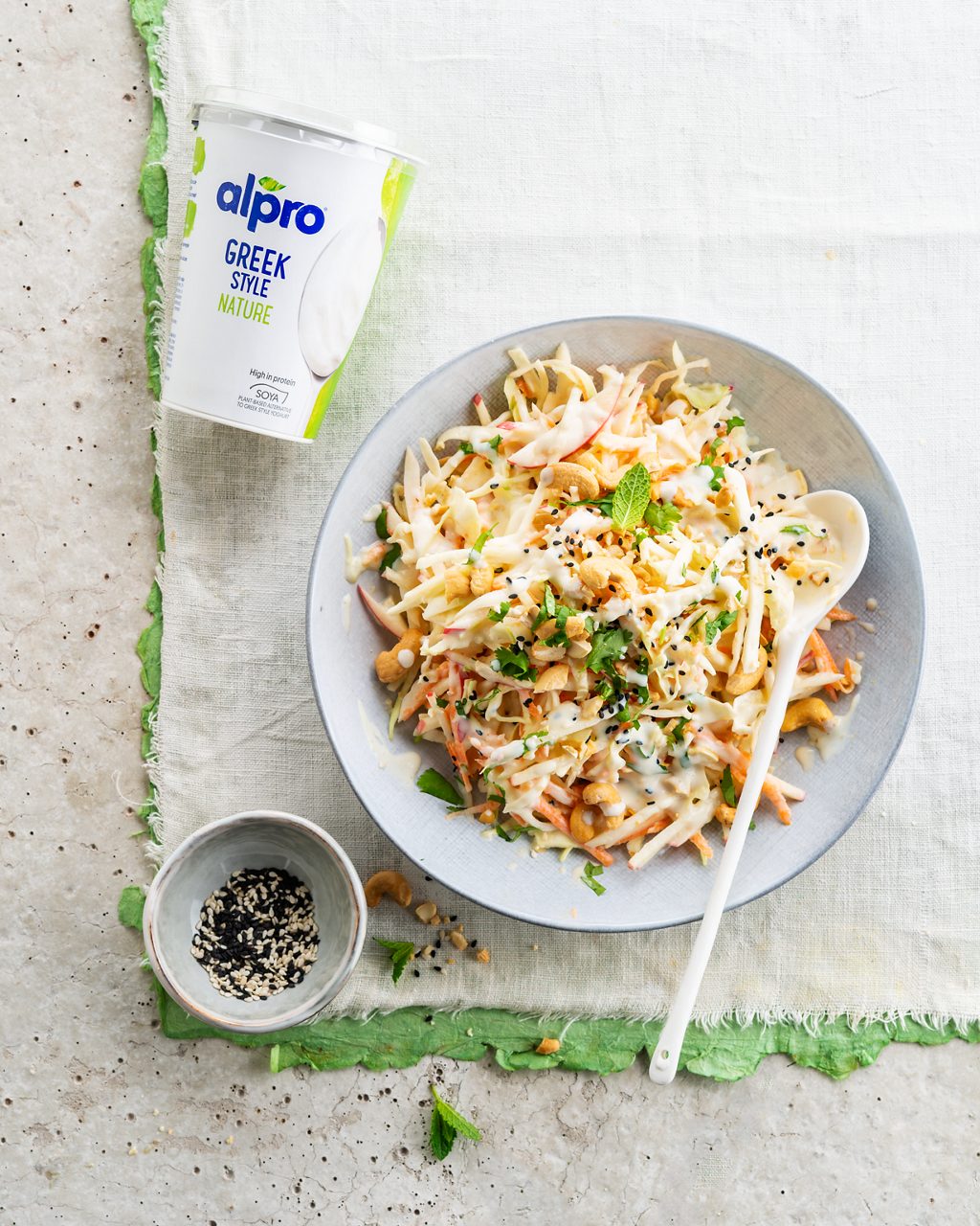 87E66D44-E1DF-42B9-82C886309DFC915E<br>A_GFY_NA_Master_Recipe_Image_VeganColeslaw_4x5__PBAY_NA_Soy_NA_Pot_500g_HR_vertical-145.tif<br>Vegan Coleslaw
Crisp, crunchy and 100% plant-based, made with Alpro Plain soya alternative to Greek Style yogurt
"The veg:
400g mixed white and oxheart/sweetheart/pointed cabbage
1 large carrot, peeled
1 red apple
60g cashew nuts, salted and roasted
2 tbsp sesame seeds, mixed 
handful of mint and coriander leaves

The dressing: (vary the amounts to taste)
400g Alpro Plain soya alternative to Greek Style yogurt
4 tbsp white balsamic vinegar
1 tsp agave syrup 
1 lemon, zest and juice 
½ garlic clove
1 tsp ground cumin"
"1. Prep the veggies. Finely chop the cabbage and coarsely grate the carrot. Slice the apple into julienne strips. Then pop the whole lot into a large bowl and toss together. 
2. Now for the dressing. Mix the Alpro Plain soya alternative to Greek Style yogurt, balsamic vinegar, agave syrup, lemon juice and zest, finely chopped garlic and cumin and season with salt and pepper.
3. Pour the dressing over the salad mix and stir through until all the veggies are nicely coated. Finely chop the herbs, add them to the mix and leave for 10 minutes for all that fab flavour to blend together. 
4. Finally, for a little extra crunch coarsely chop the cashew nuts and scatter over the salad along with the sesame seeds. The perfect side for summer BBQs!"
lactose free, veggie, vegan, gluten free
/vegan-coleslaw
(Recipe type: SIDEDISH (Prep time: 25 min) (servings: +/- 4 persons) (season: all year) (pool: 1) NOT TO BE TRANSLATED
/
/
/
/
Alpro Plain soya alternative to Greek Style yogurt
Alpro, Alpro recipe, side dish, coleslaw, cabbage, summer, BBQ