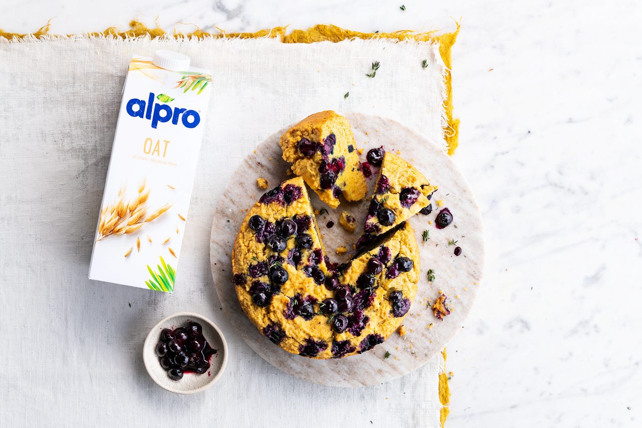 3CE9D988-F02B-4EBA-8859928AE7EB9A7E<br>A_DeliciouslyGFY_NA_Master_Recipe_Blueberrypolentacake_image_drinks_oat_NA_TetrapackUHT_1L_NA_horizontaal-295.tif<br>Blueberry Polenta Cake 
Moist, moreish, berrylicious! Made with Alpro Oat drink 
"200g plain flour
165g finely ground polenta 
5ml baking powder
½ tsp bicarbonate of soda 
2.5g salt
250ml Alpro Oat drink
1 tbsp vanilla essence
65g maple syrup + 1 tbsp extra
80 g melted Alpro baking and frying 
250g blueberries + 100g extra for garnish 
A small sprig of thyme 
"
"1. First, the prep. Preheat your oven to 180°C (fan). Line an 18cm cake tin with baking paper, or brush with Alpro baking and frying. 
2. In a large bowl, mix together the flour, polenta, baking powder, bicarb and salt. In a separate jug or bowl, whisk together the Alpro Oat drink, vanilla, maple syrup and coconut oil. 
Add the liquid ingredients to the dry ingredients and stir till it's all well mixed together. 
3. Pour the cake mix into your prepped tin, and scatter on 3/4 of the berries. Push them down into the batter and then arrange the rest on the top. Bake in the oven for 30-35 minutes, till a toothpick comes out clean. 
4. While the cake's in the oven, pop the extra berries and maple syrup into a small saucepan with the thyme leaves. Add a little water and bring to the boil. Cook for 5 minutes or until it turns into a lovely, oozy syrup. 
5. Take the cake out of the oven and straightaway spread the cooked berry syrup over the top. Leave to cool for a couple of minutes before removing from the tin. Serve it while it's still warm with a dollop of something plant-based and creamy. Delicious!"
veggie, vegan, lactose free
/blueberry_polenta_cake
(Recipe type: dessert/snack (Prep time: 10 min) (baking time: 30-35 min) (cooling time: 5 min) (servings: 6-8 people) (season: all year round)