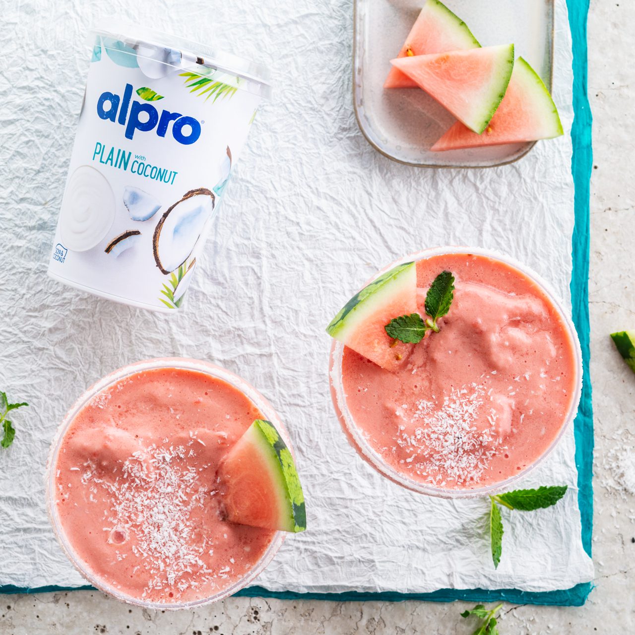 55837D47-8659-4E97-A032C4C291EE8F93<br>A_GFY_NA_Master_Recipe_Image_WatermelonMocktail_1x1__Drinks_NA_Coconut_NA_TetraUHT_1l_HR_189.tif<br>Virgin Watermelon Margarita 
Whip up this watermelon wonder with Alpro Plain with Coconut soya alternative to yogurt & Alpro Coconut drink 
"250g Alpro Plain with Coconut soya alternative to yogurt
100ml Alpro Coconut drink
450g watermelon (for freezing) + extra to decorate
1 lime (juice) 
5g mint leaves 
3 tbsp dessicated coconut "
"1. Chop the watermelon into small cubes, removing all the pips. Pop into a freezer-safe container, and freeze. 
2. Once they’re frozen, they’re ready to go into a blender along with the Alpro Plain with coconut and Alpro Coconut drink, the lime juice and mint leaves. Blitz until smooth and slushy. (if you don’t have a blender, a jug and a hand-held wand will do just as well.) 
3. Decorate your glasses by dipping the rims in water and then into the desiccated coconut. 
4. Pour in the mocktail and garnish with small slices of watermelon and mint leaves. Cheers!"
lactose free, veggie, vegan, gluten free
/frozen-watermelon-mocktail
(Recipe type: DRINKS  (Freezing time: 3hours) (Prep time: 15 min)  (servings: +/- 4 persons) (season: spring - summer) (pool: 1) NOT TO BE TRANSLATED
/
/
/
/
Alpro Plain with Coconut soya alternative to yogurt, Alpro Coconut Drink
Alpro, Alpro recipe, coconut, drink, mocktail, frozen, watermelon