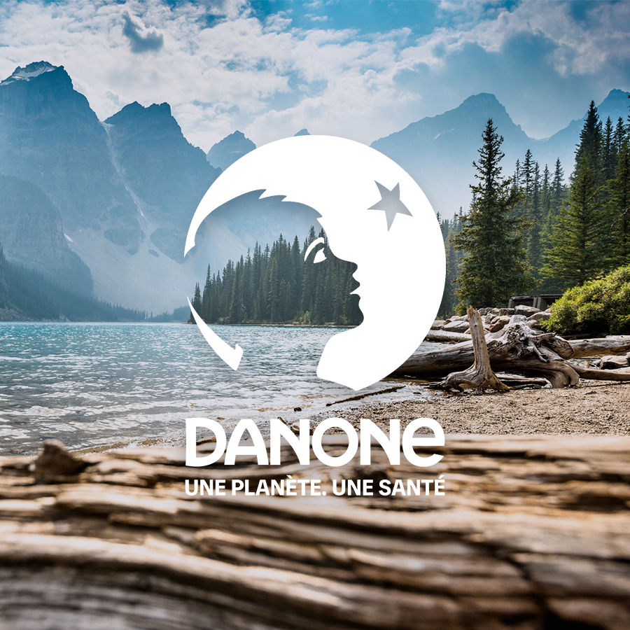 Image d'un paysage avec des arbres et des montagnes, avec le logo Danone affiché en bleu à l'avant-plan.