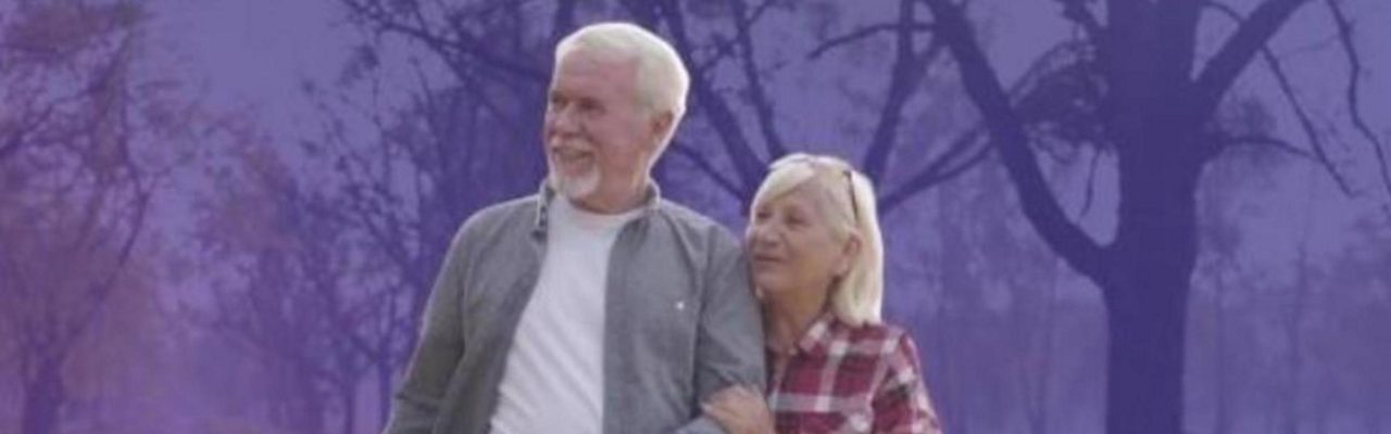 Twee oudere volwassenen wandelen samen buiten in een natuurlijke omgeving.